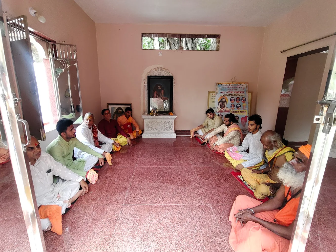 Pandit Tarun Ji Maharaj at a temple beside a decorated Nandi statue